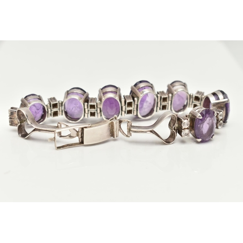 30 - AN AMETHYST BRACELET, designed as a graduated line of oval amethysts, each interspaced by two circul... 