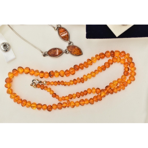 100 - FOUR ITEMS OF JEWELLERY, to include an amber polished pebble necklace, an amber polished bead neckla... 