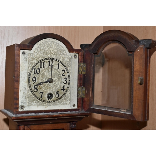 354 - A MANTEL CLOCK IN THE FORM OF A GRANDFATHER CLOCK, with black Arabic numerals on a painted metal dia... 