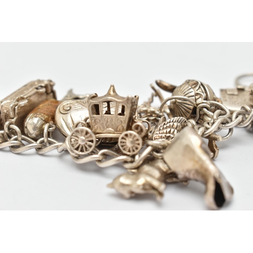 28 - A HEAVY SILVER CHARM BRACELET, curb link bracelet fitted with multiple charms in forms such as a boo... 