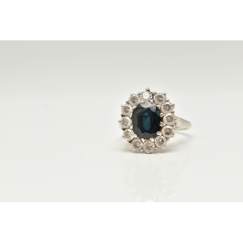 43 - A 9CT WHITE GOLD CLUSTER RING, of an oval design, set to the centre with a deep blue oval cut sapphi... 