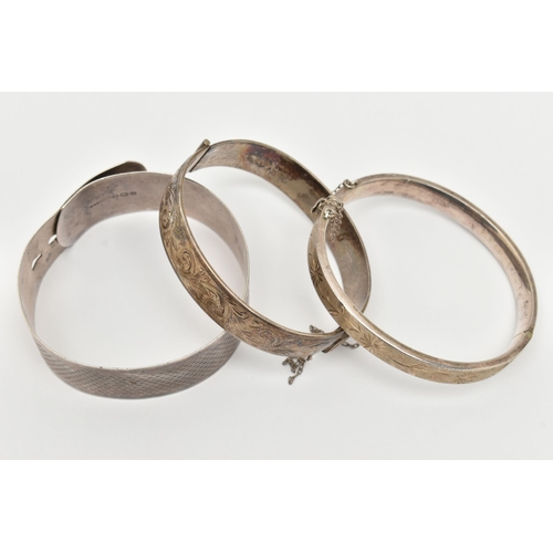 50 - THREE SILVER BANGLES, the first a wide engine turned pattern belt style bangle, hallmarked Birmingha... 