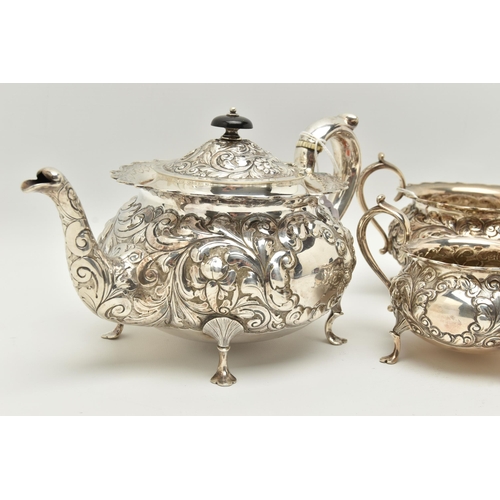 145 - A LATE VICTORIAN SILVER THREE PIECE TEA SET OF CIRCULAR FORM WITH WAVY RIMS, ornately cast with foli... 