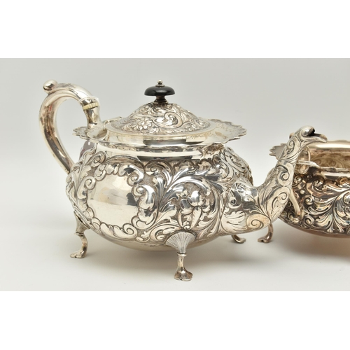 145 - A LATE VICTORIAN SILVER THREE PIECE TEA SET OF CIRCULAR FORM WITH WAVY RIMS, ornately cast with foli... 