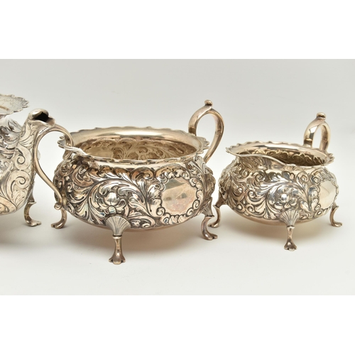 145 - A LATE VICTORIAN SILVER THREE PIECE TEA SET OF CIRCULAR FORM WITH WAVY RIMS, ornately cast with foli... 