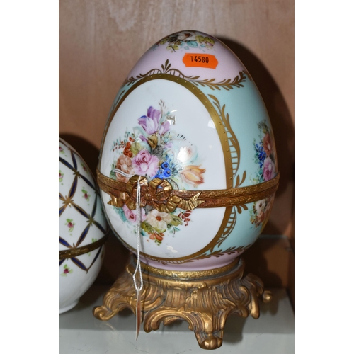 391 - TWO LIMOGES PORCELAIN DECORATED EGGS, the larger egg on a gilt metal base is painted with flowers on... 