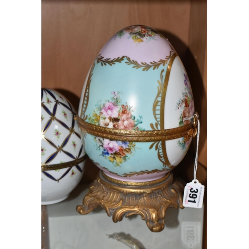 391 - TWO LIMOGES PORCELAIN DECORATED EGGS, the larger egg on a gilt metal base is painted with flowers on... 