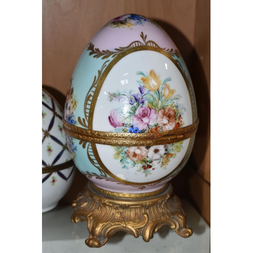 391 - TWO LIMOGES PORCELAIN DECORATED EGGS, the larger egg on a gilt metal base is painted with flowers on... 