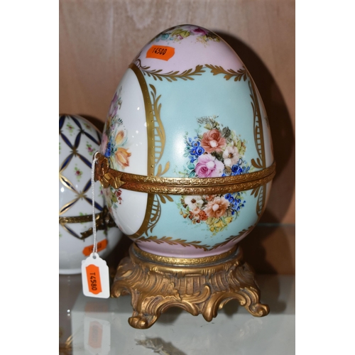 391 - TWO LIMOGES PORCELAIN DECORATED EGGS, the larger egg on a gilt metal base is painted with flowers on... 