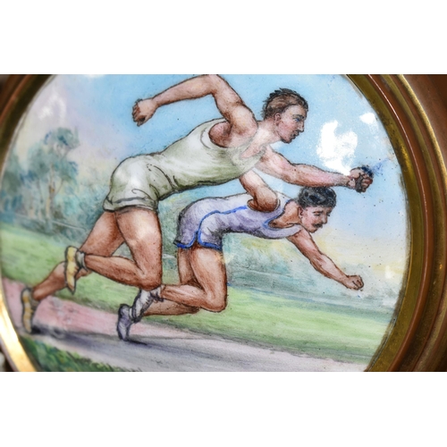 404 - AN EARLY 20TH CENTURY SPORTING  ENAMEL PLAQUE DEPICTING TWO MALE ATHLETES IN A SPRINT, brass coated ... 