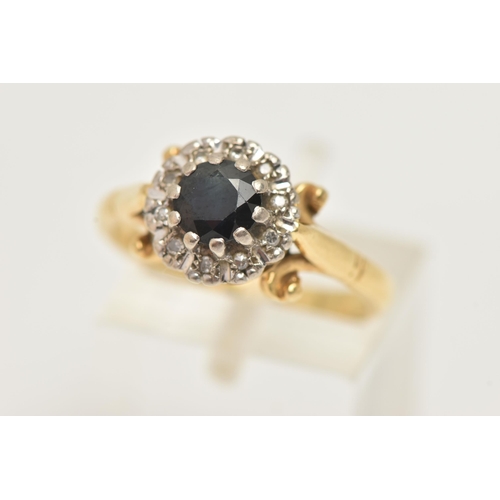 27 - AN 18CT GOLD SAPPHIRE AND DIAMOND CLUSTER RING, set with a circular cut sapphire, bordered by ten si... 