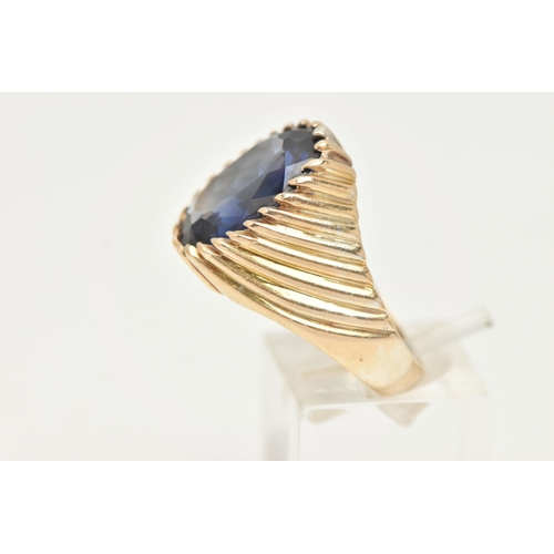 40 - A GEM SET SIGNET RING, designed with an oval cut blue synthetic sapphire in a tapered ring mount wit... 