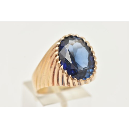 40 - A GEM SET SIGNET RING, designed with an oval cut blue synthetic sapphire in a tapered ring mount wit... 