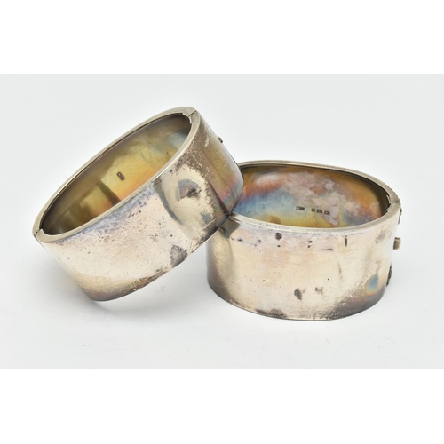 48 - TWO SILVER HINGED BANGLES, the first a late Victorian wide bangle with belt detail, push button inte... 