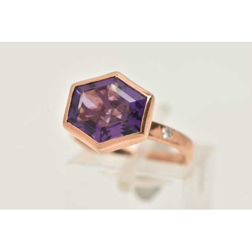 57 - A 9CT GOLD GEM SET RING, an elongated hexagon cut amethyst, bezel set in rose gold, flanked with two... 