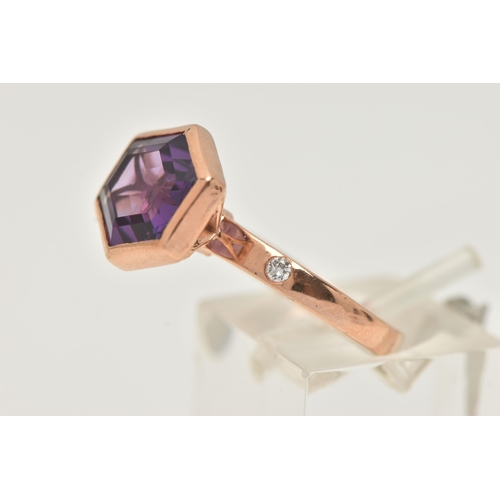 57 - A 9CT GOLD GEM SET RING, an elongated hexagon cut amethyst, bezel set in rose gold, flanked with two... 