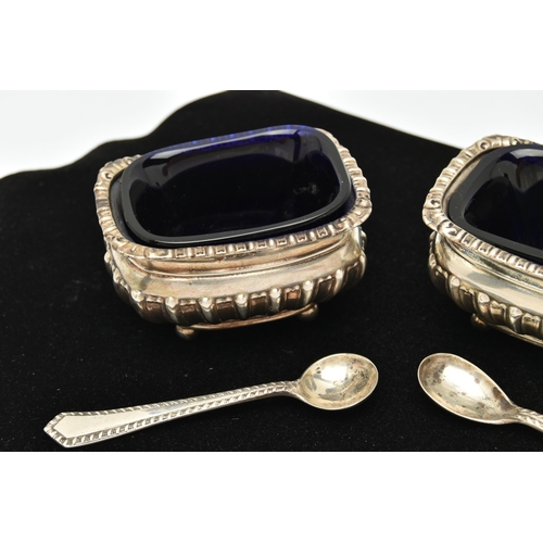 131 - TWO SILVER SALTS WITH SPOONS, two rectangular embossed salts with gadrooned rims, both raised on fou... 