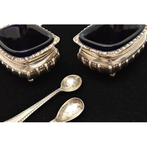 131 - TWO SILVER SALTS WITH SPOONS, two rectangular embossed salts with gadrooned rims, both raised on fou... 