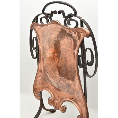 60A - AN ARTS AND CRAFTS STYLE PLANISHED COPPER AND WROUGHT IRON FIRE GUARD, the wrought iron scrolling fr... 