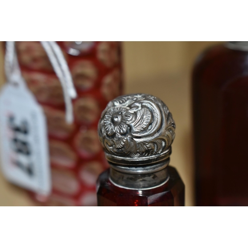 387 - THREE VICTORIAN CRANBERRY GLASS SCENT BOTTLES, comprising two cut cranberry glass bottles with flora... 