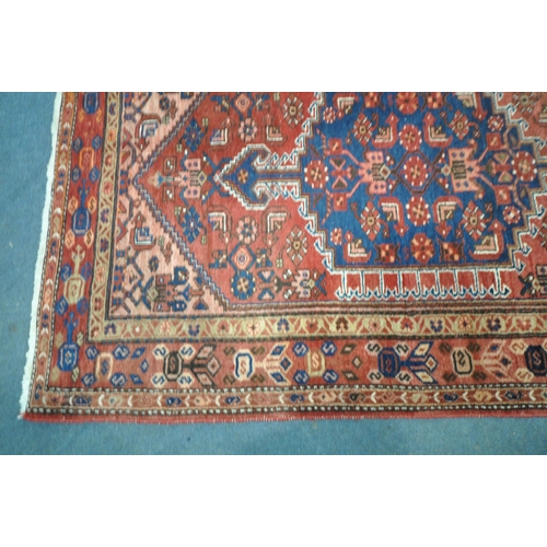 1262 - A PERSIAN RED RUG, with a repeating pattern, and multi strap, 202cm x 130cm (condition report: sun b... 