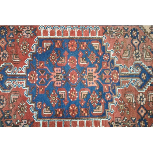 1262 - A PERSIAN RED RUG, with a repeating pattern, and multi strap, 202cm x 130cm (condition report: sun b... 