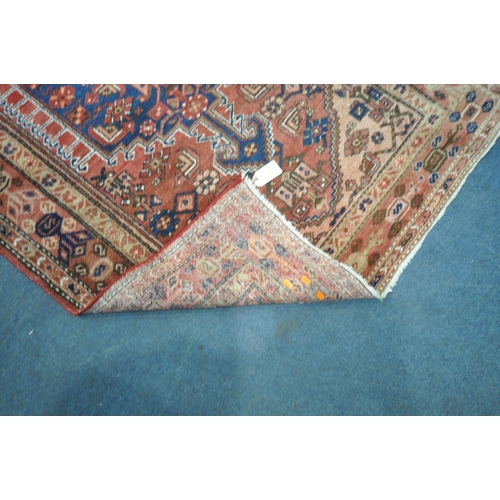 1262 - A PERSIAN RED RUG, with a repeating pattern, and multi strap, 202cm x 130cm (condition report: sun b... 