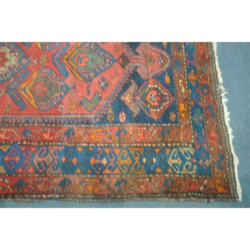 1264 - A PERSIAN RED RUG, the centre with seven shaped patterns, repeating design that's surrounds, and a m... 