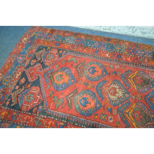 1264 - A PERSIAN RED RUG, the centre with seven shaped patterns, repeating design that's surrounds, and a m... 