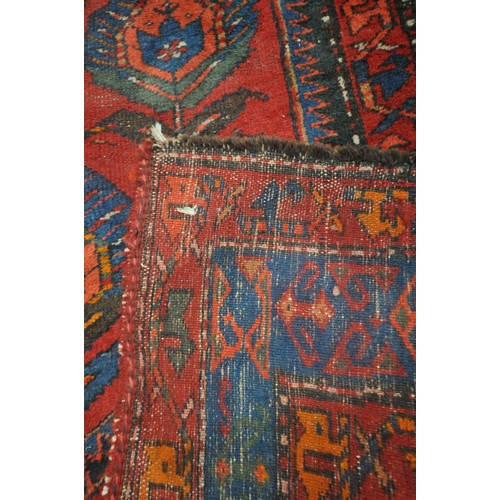 1264 - A PERSIAN RED RUG, the centre with seven shaped patterns, repeating design that's surrounds, and a m... 