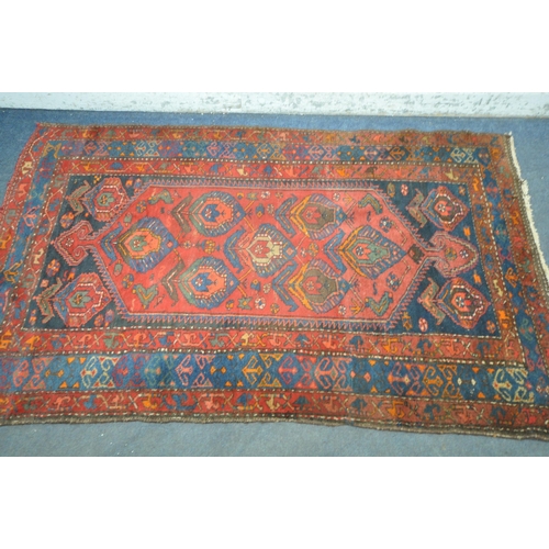 1264 - A PERSIAN RED RUG, the centre with seven shaped patterns, repeating design that's surrounds, and a m... 