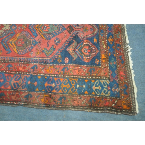 1264 - A PERSIAN RED RUG, the centre with seven shaped patterns, repeating design that's surrounds, and a m... 