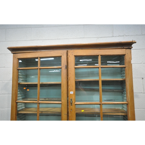 1261 - A 19TH CENTURY PINE BOOKCASE,  the two glazed doors enclosing an arrangement of shelving, above two ... 