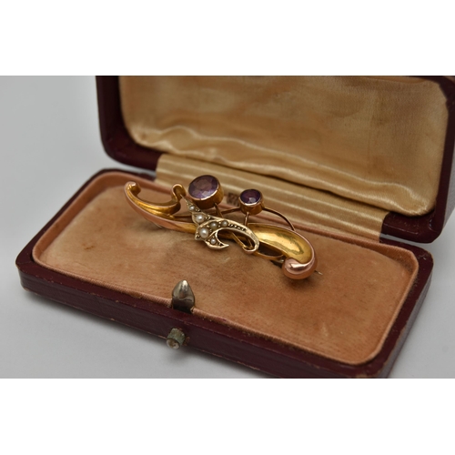 22 - AN EARLY 20TH CENTURY BROOCH, a scrolling yellow gold brooch set with two circular cut amethysts and... 