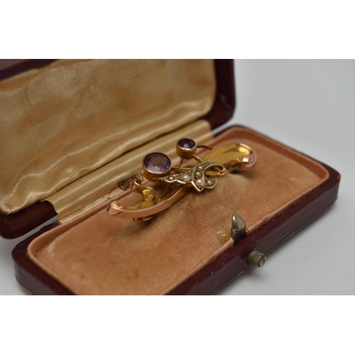 22 - AN EARLY 20TH CENTURY BROOCH, a scrolling yellow gold brooch set with two circular cut amethysts and... 