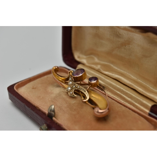 22 - AN EARLY 20TH CENTURY BROOCH, a scrolling yellow gold brooch set with two circular cut amethysts and... 