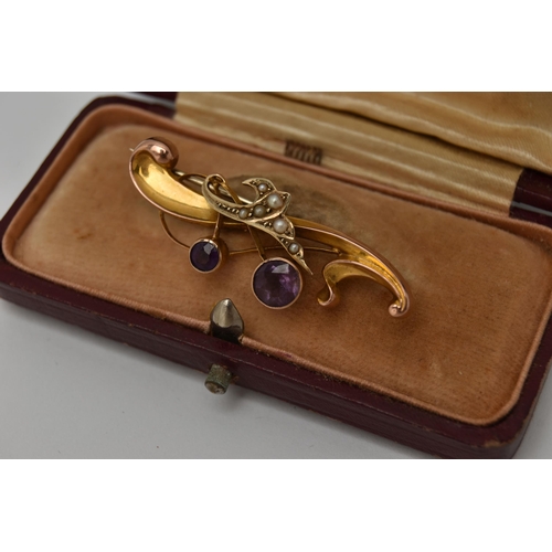 22 - AN EARLY 20TH CENTURY BROOCH, a scrolling yellow gold brooch set with two circular cut amethysts and... 