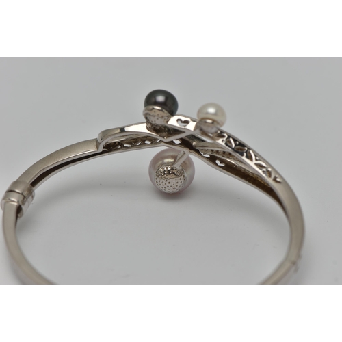 52 - A WHITE METAL HINGED BANGLE, open work design set with three imitation pearls, fitted with a magneti... 