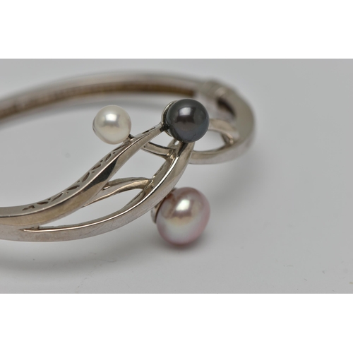 52 - A WHITE METAL HINGED BANGLE, open work design set with three imitation pearls, fitted with a magneti... 