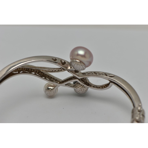 52 - A WHITE METAL HINGED BANGLE, open work design set with three imitation pearls, fitted with a magneti... 