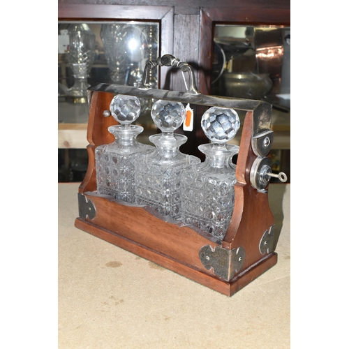 396 - A TWENTIETH CENTURY TANTALUS, containing three cut glass square decanters, plated handle and mounts,... 