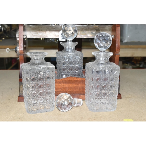 396 - A TWENTIETH CENTURY TANTALUS, containing three cut glass square decanters, plated handle and mounts,... 