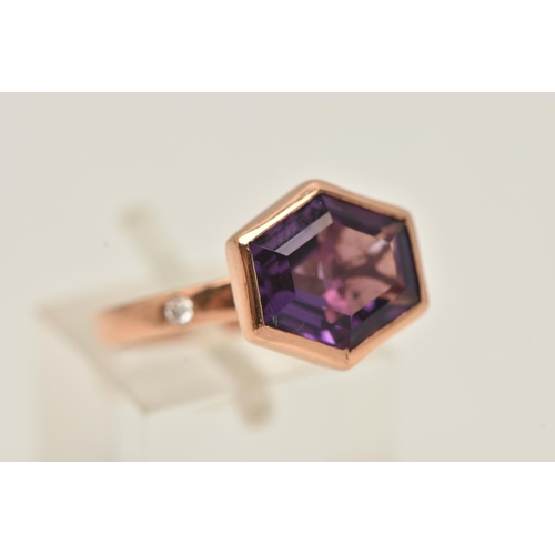 11 - A 9CT GOLD GEM SET RING, an elongated hexagon cut amethyst, bezel set in rose gold, flanked with two... 