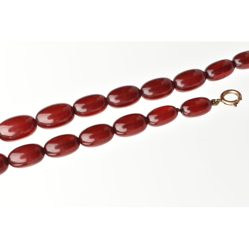 33 - A BAKELITE NECKLACE, twenty six cherry amber Bakelite oval beads, approximate length of largest bead... 