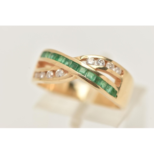 37 - A MODERN YELLOW METAL DIAMOND AND EMERALD DRESS RING, the ring is of cross over design, set with a r... 