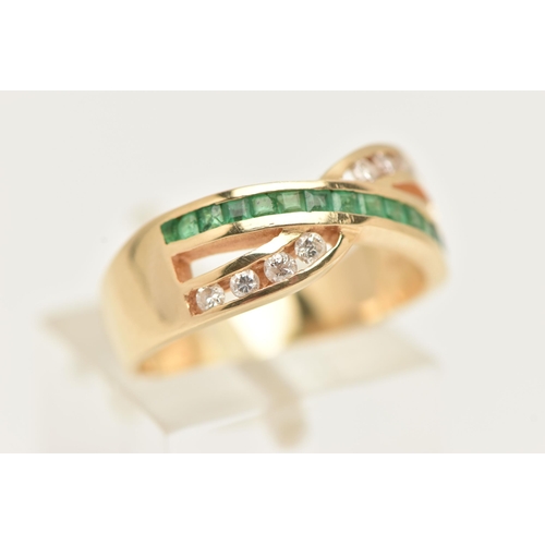 37 - A MODERN YELLOW METAL DIAMOND AND EMERALD DRESS RING, the ring is of cross over design, set with a r... 