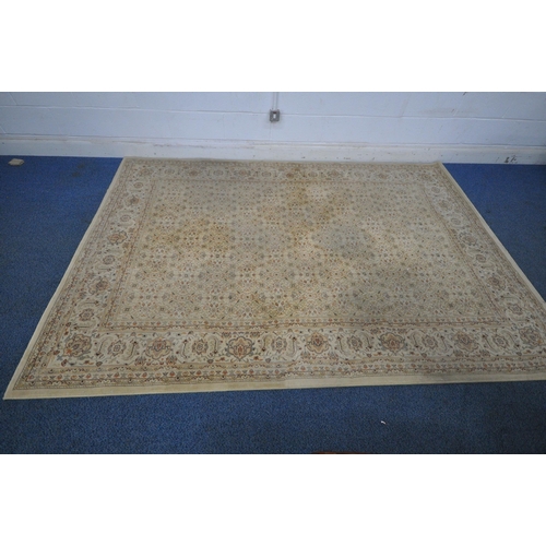 1212 - A LARGE BEIGE RECTANGULAR WOOLEN RUG, with repeating floral patterns, and a multi-strap border, 290c... 