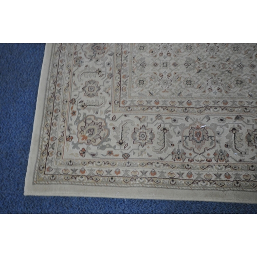 1212 - A LARGE BEIGE RECTANGULAR WOOLEN RUG, with repeating floral patterns, and a multi-strap border, 290c... 