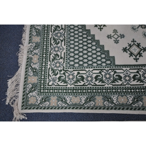 1213 - A RECTANGULAR CREAM AND GREEN WOOLEN RUG, 244cm x 172cm, along with a matching runner (condition rep... 