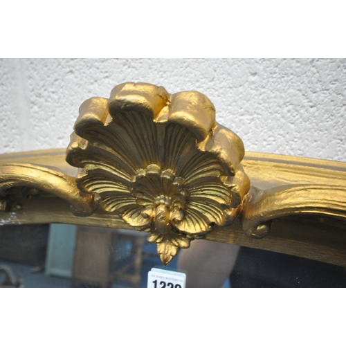 1229 - A LARGE GILT FRAMED ARCHED OVERMANTEL MIRROR, with scrolled crest and side details, width 138cm x de... 